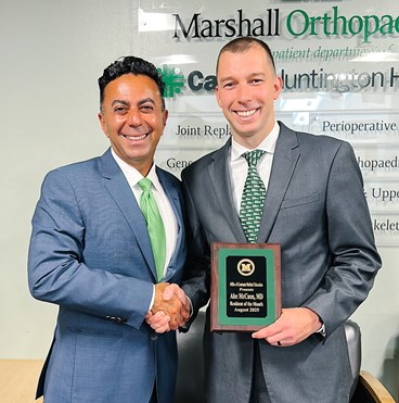 Dr. Alec McCann receives his Resident of the Month plaque from Dr. Ali Oliashirazi, chair of the department of orthopaedic surgery at the Joan C. Edwards School of Medicine.
